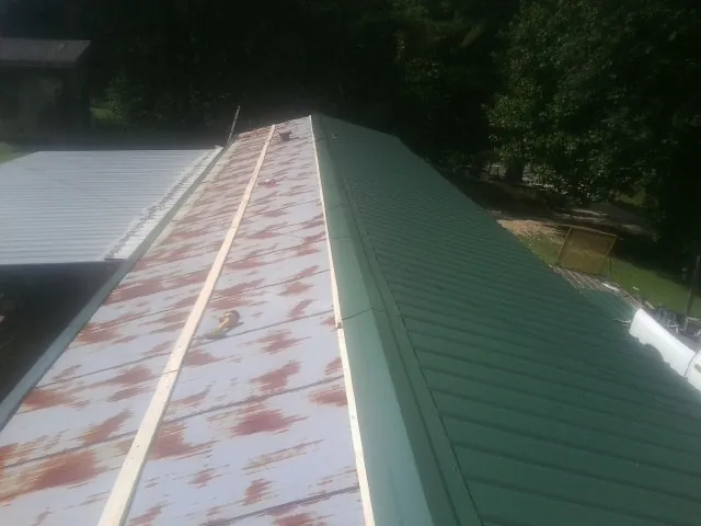 Old rusted panels beside newly installed green metal roofing — Wind Damage Roof Repair by Roofing Brothers in New Smyrna Beach