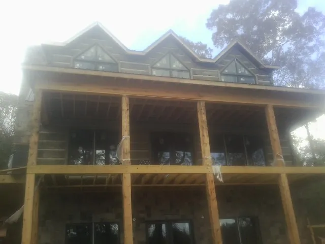 Dormers and porch framing on a large log home under construction — Roof Coating work by our crew in New Smyrna Beach
