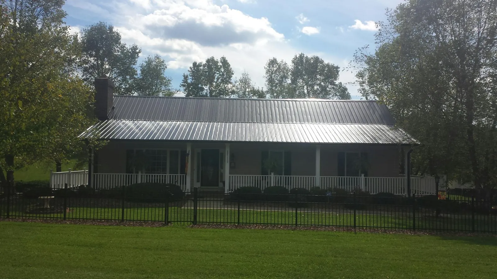 Gray metal roof on a brick ranch with a full width front porch — Gutter Guard Installation work by our crew in New Smyrna Beach