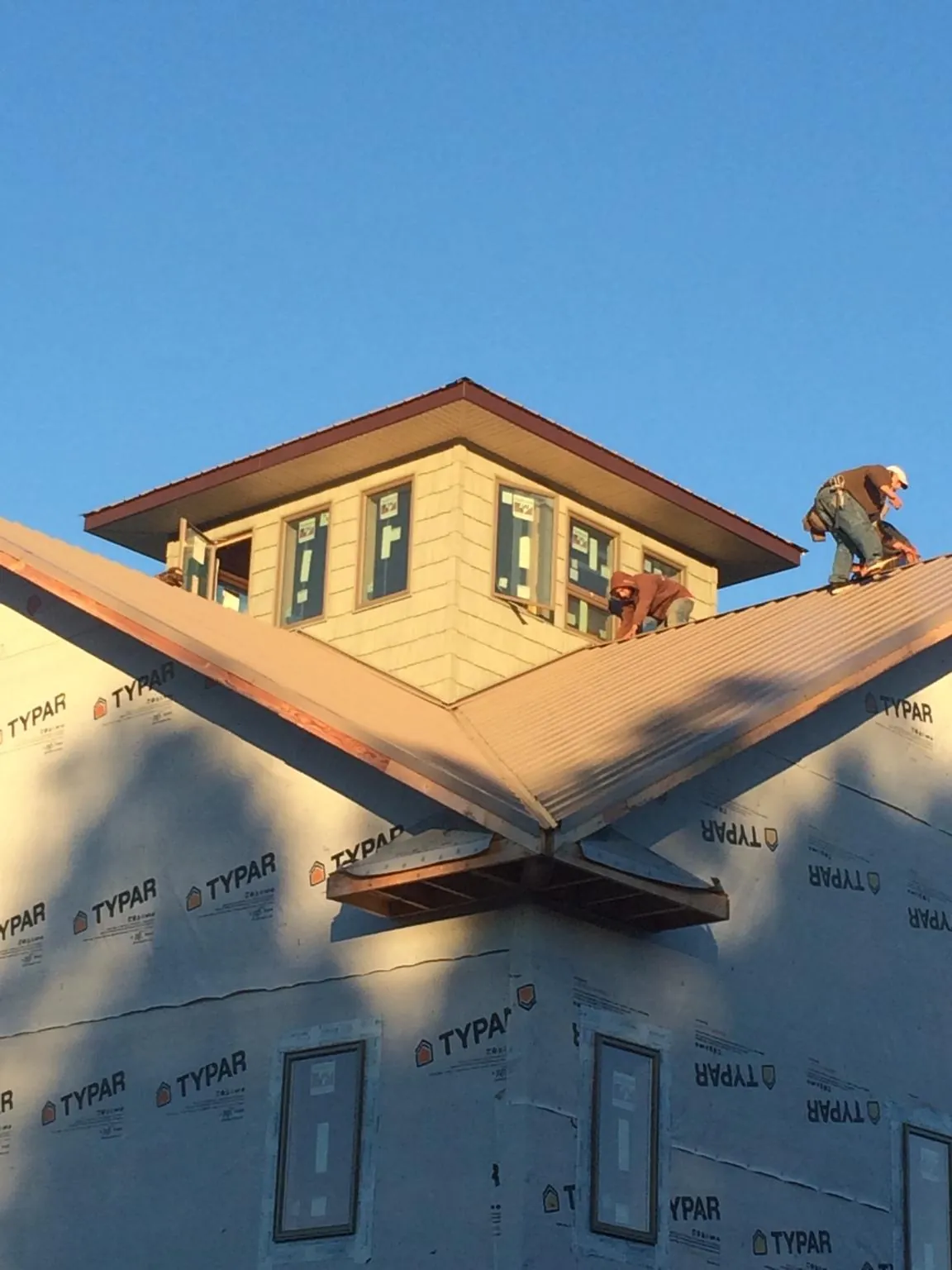 Roofers working around a rooftop cupola on a new metal roof at sunset — Roof Waterproofing in New Smyrna Beach by Roofing Brothers